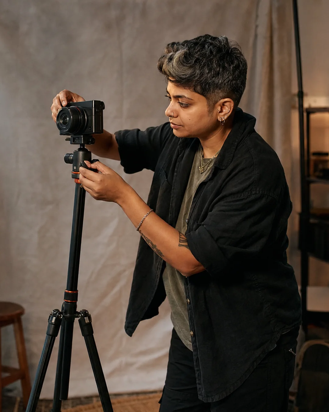 A solo creator adjusts a compact camera on a tripod in a small home studio