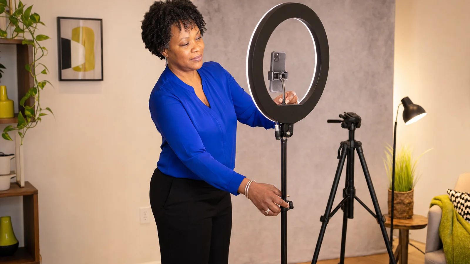 A creator adjusts a large ring light and phone mount in a warm home studio